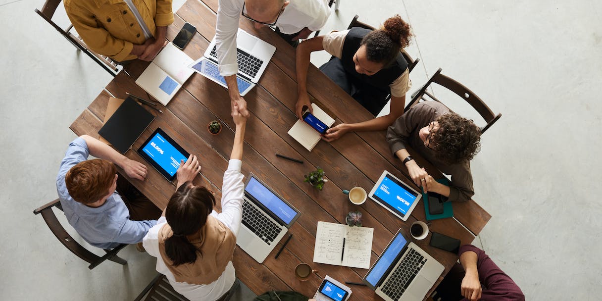 Overhead view of team meeting around a table with laptops