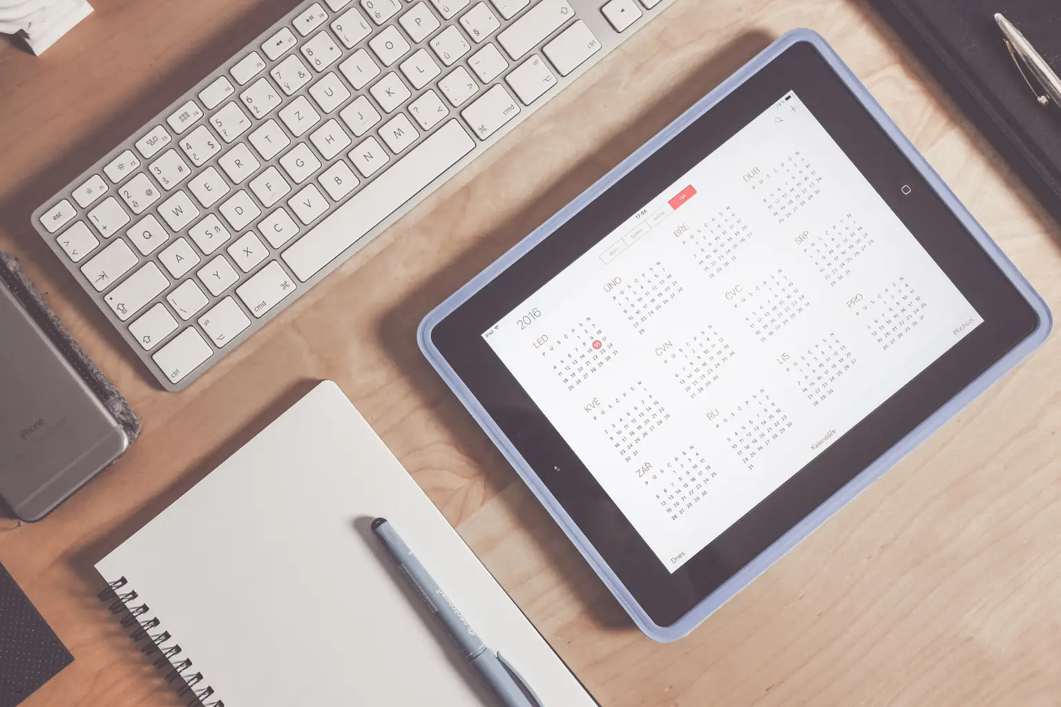 online appointment booking calendar months displayed on tablet screen beside keyboard and notebook