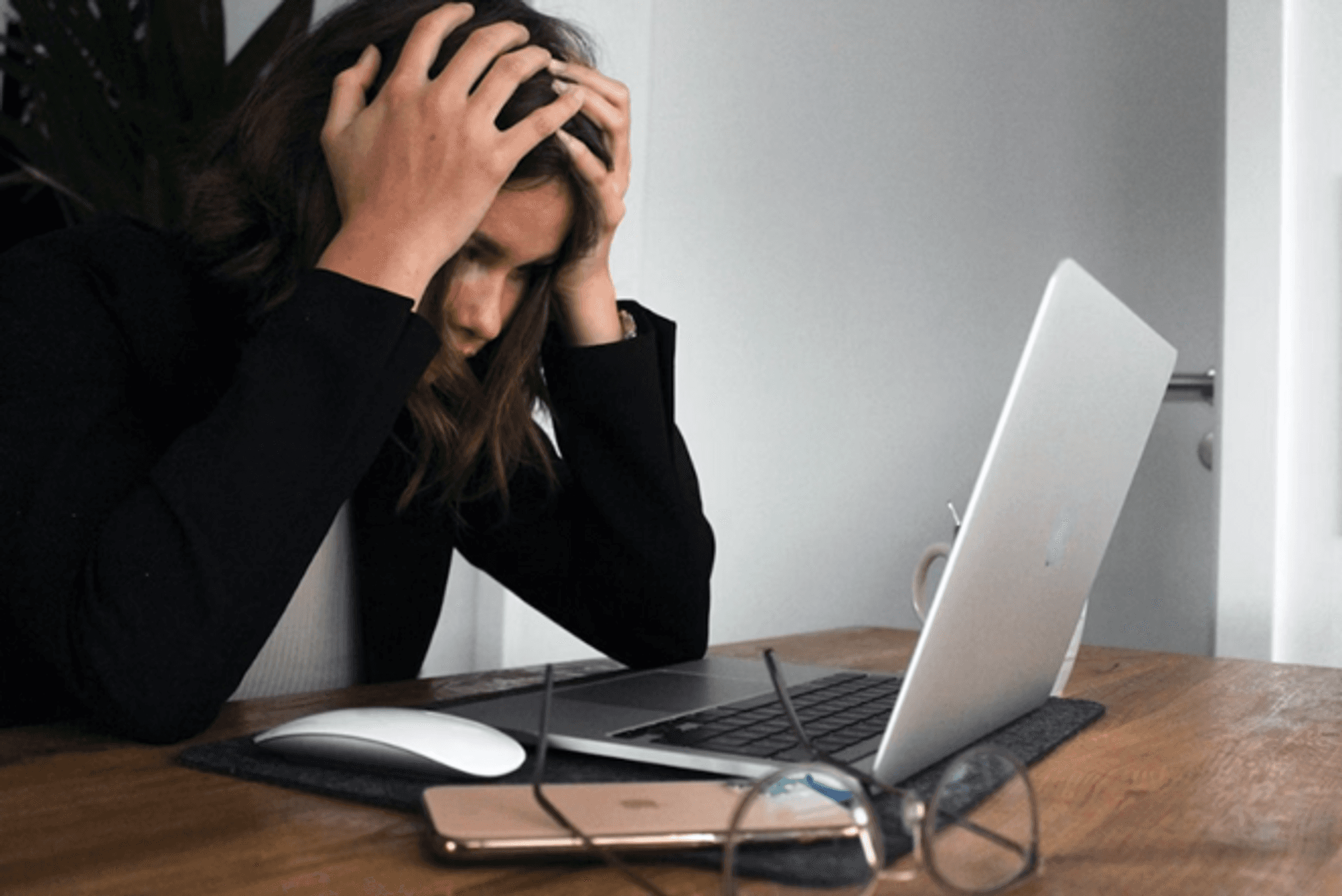 Stressed woman with head in hands at a laptop