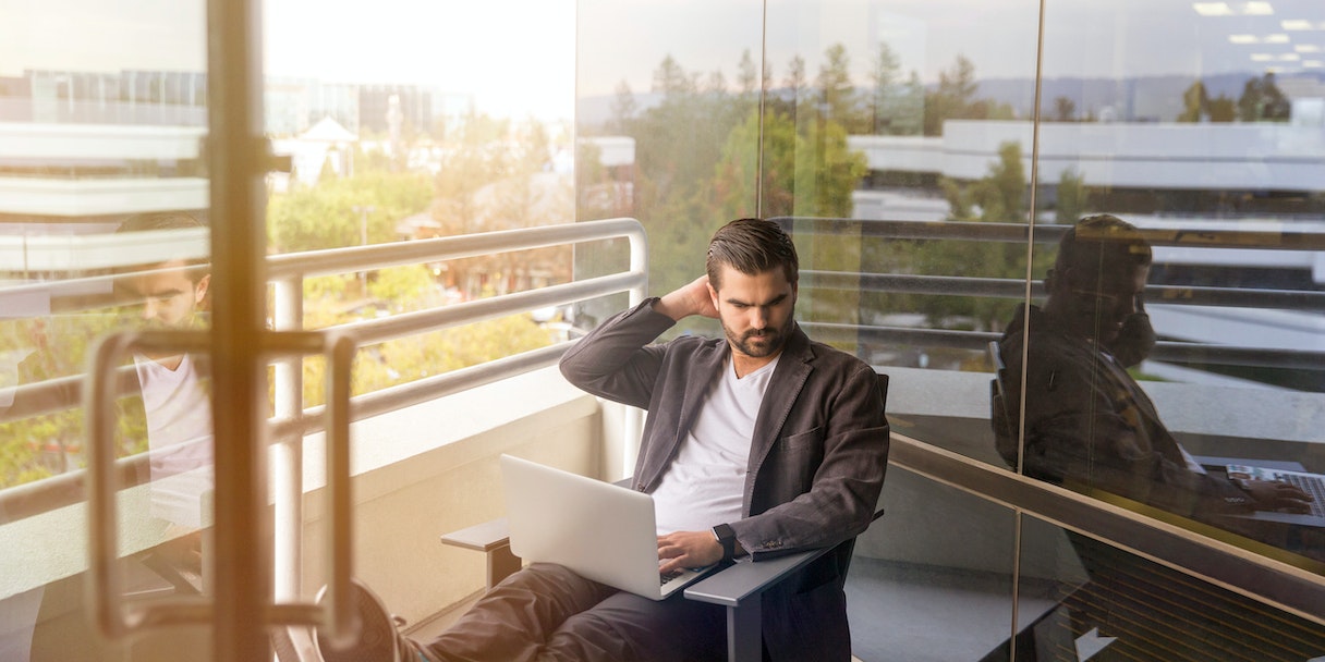 Man working on laptop on an office balcony