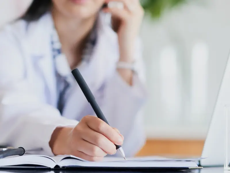 Best scheduling tools in use as a doctor takes notes in a planner while speaking on the phone.