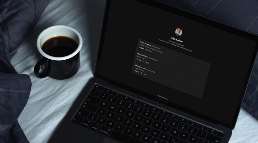 Laptop with dark scheduling app screen beside coffee mug