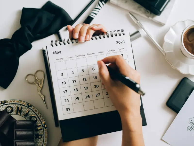 AI tools for calendar management help users plan efficiently, as shown by a person writing on a stylish desk calendar.