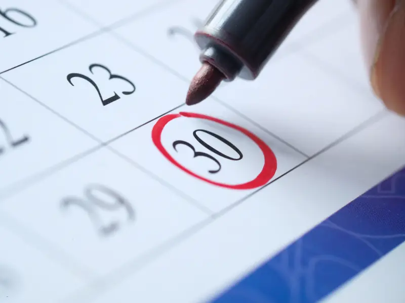 Calendar management in action with a close-up of a hand circling the 30th on a paper planner