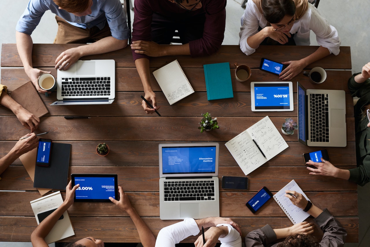 Overhead view of team meeting with laptops and tablets