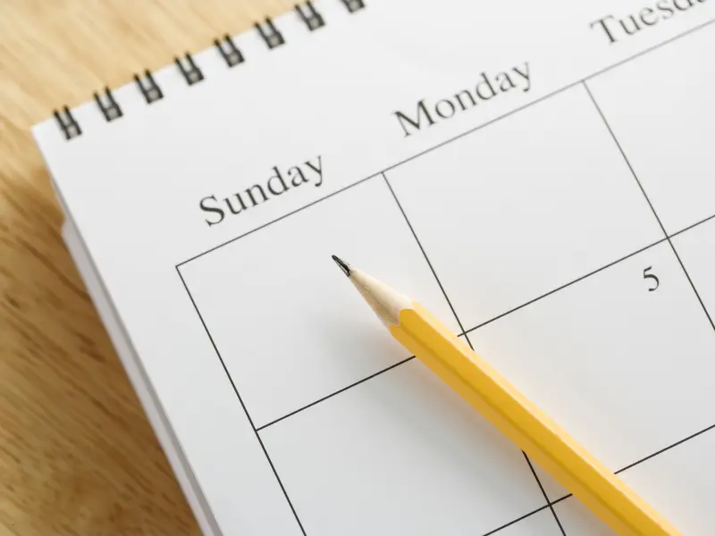 Customizable scheduling software shown with a blank spiral planner and pencil on a wooden surface