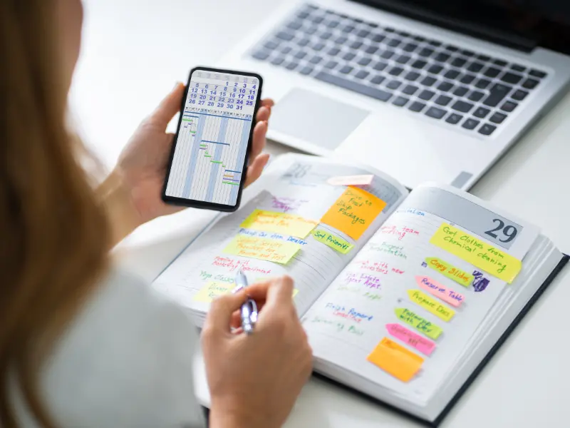 Team calendar tools shown on a phone screen and colorful planner next to a laptop