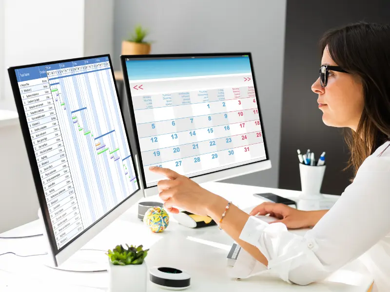 Appointment booking software interface displayed on dual monitors with a Gantt chart and calendar screen
