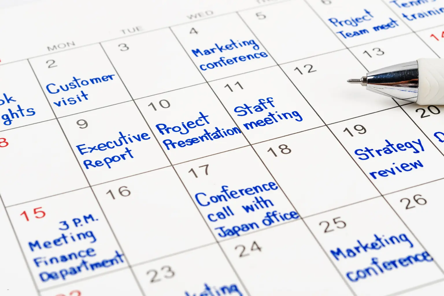 Paper wall calendar with handwritten meetings