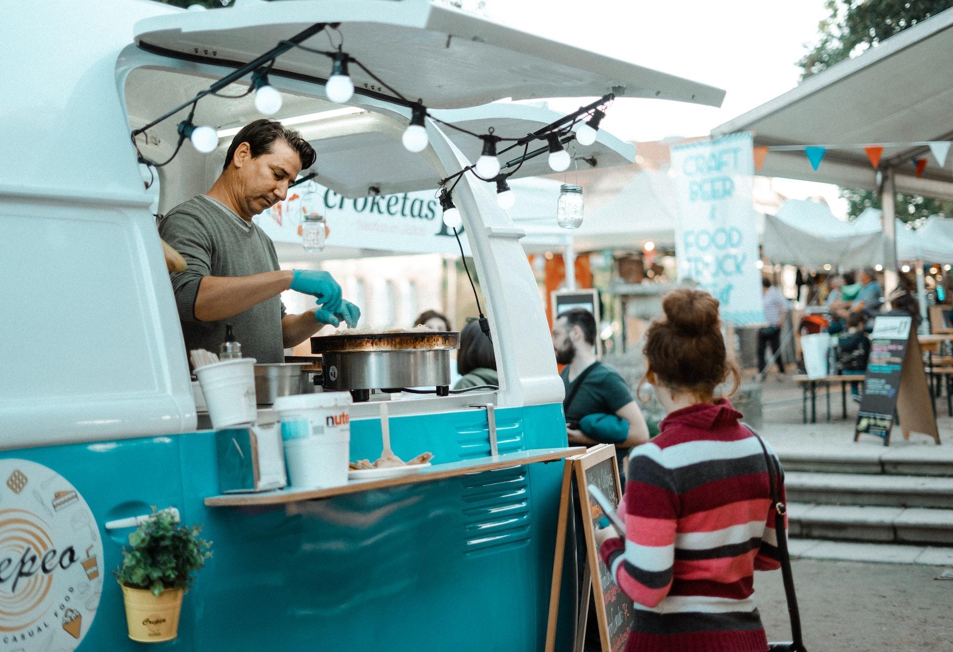 Food truck vendor serving a customer at a market