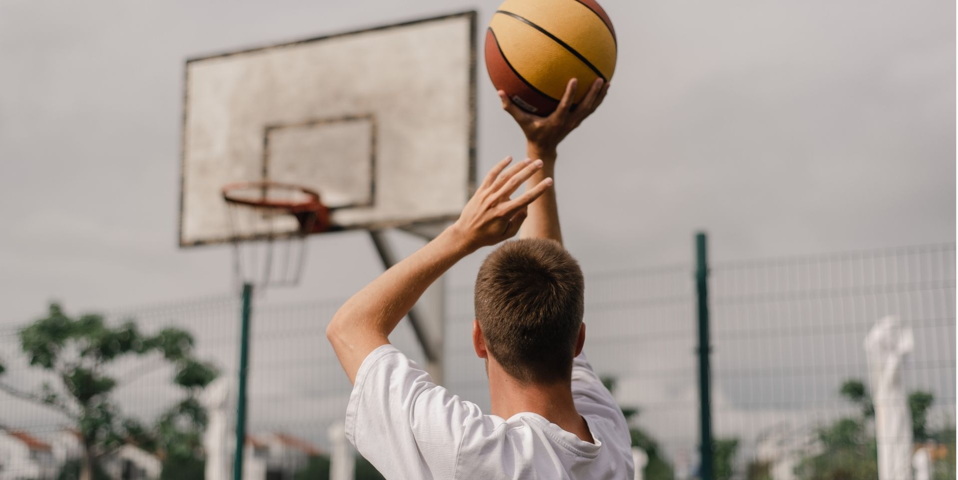 Man shooting a basketball on an outdoor court