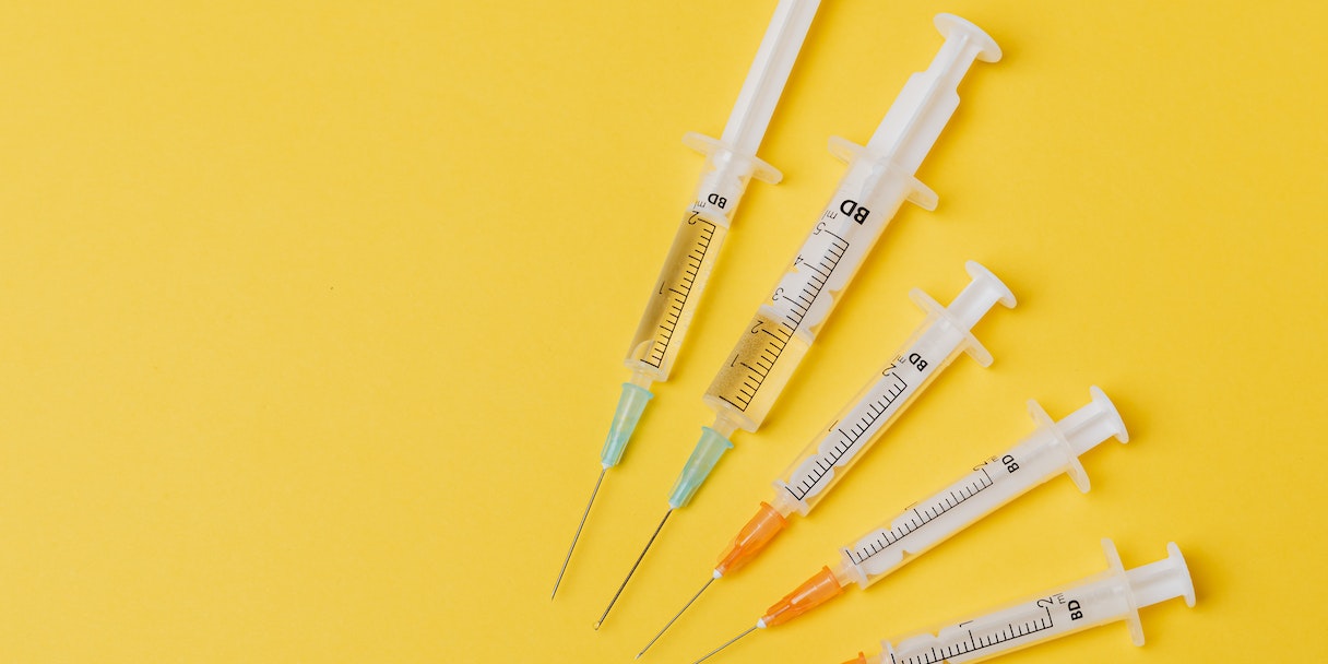 Vaccine syringes arranged on a yellow background