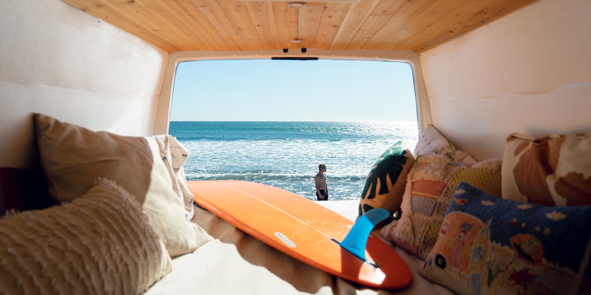 View of a beach and surfer from inside a camper van