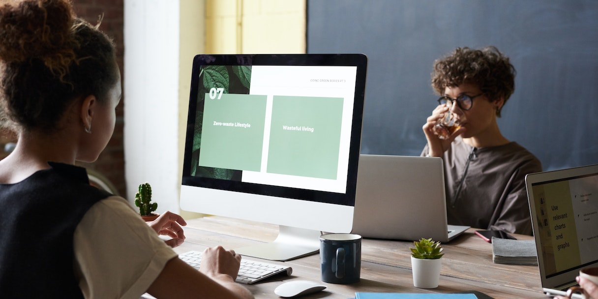 Coworkers reviewing a presentation on a desktop monitor