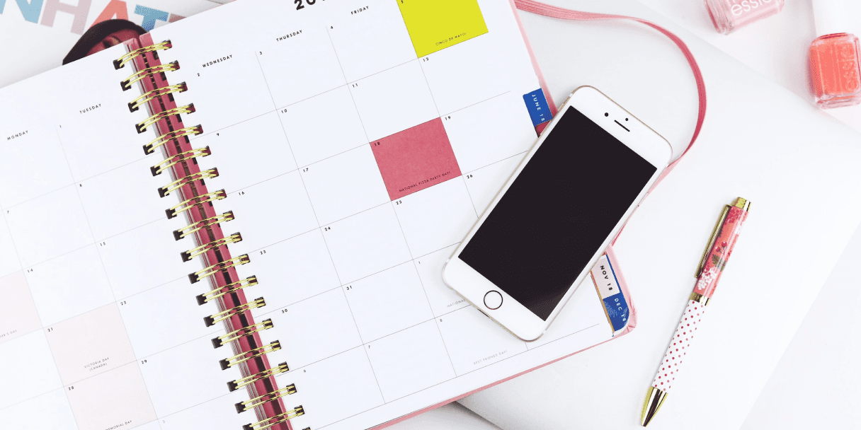 Planner calendar with smartphone and pen on desk