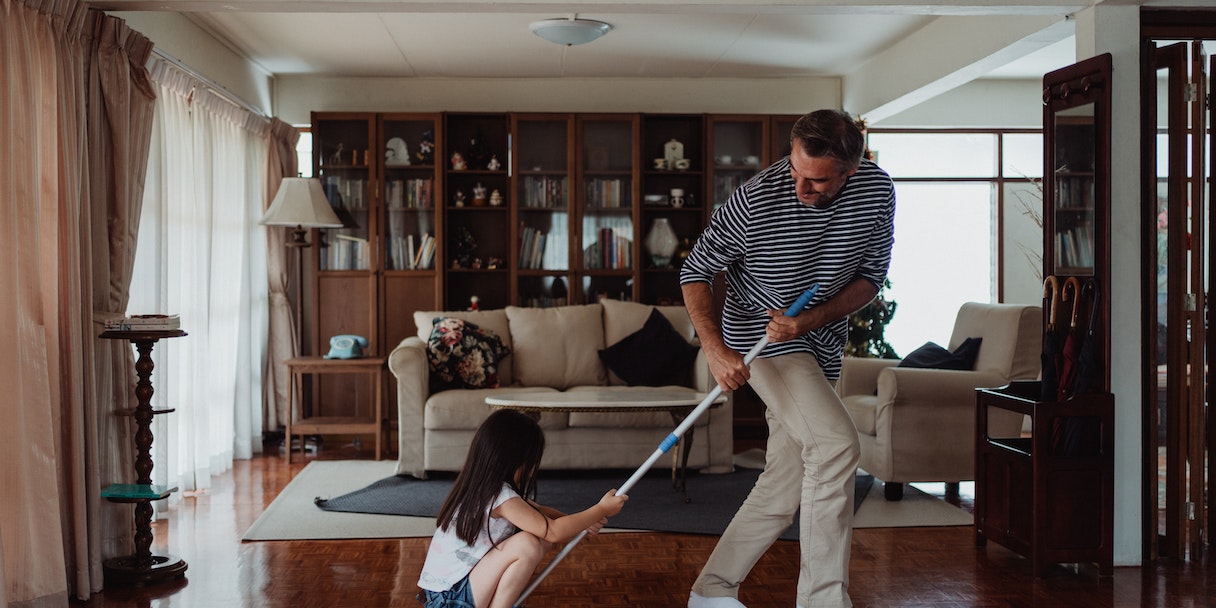 Father and daughter sweeping the living room floor together
