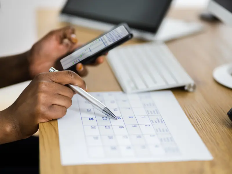 Hands marking dates on a paper calendar