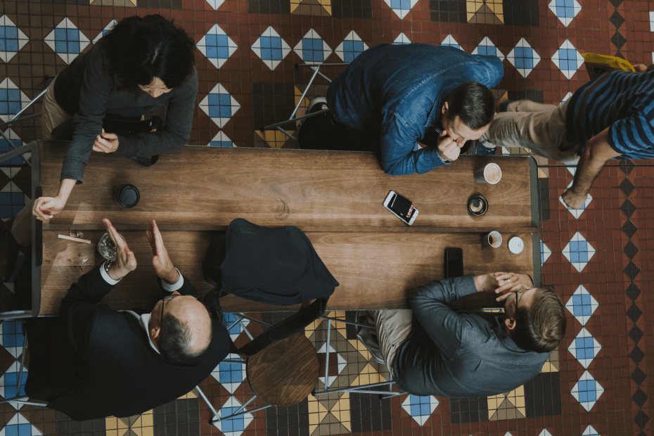 Overhead view of people meeting around a wooden table