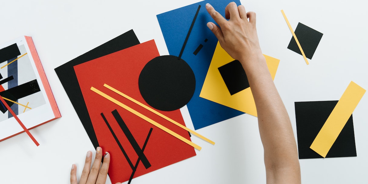 Hands arranging colorful geometric paper shapes on a table