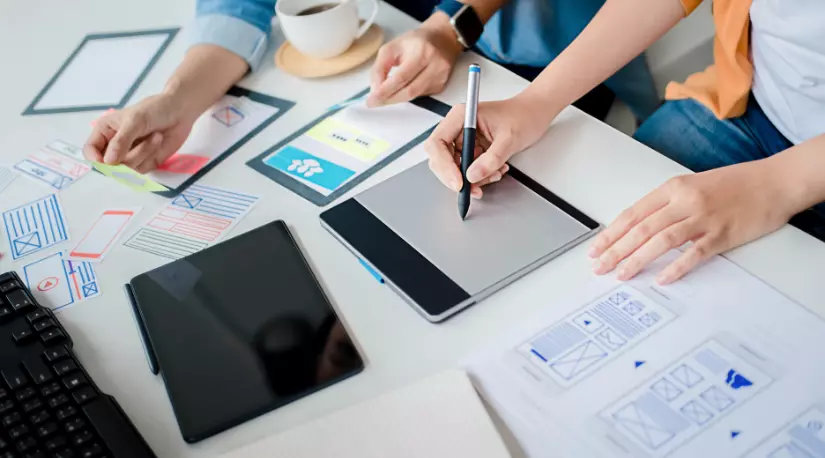 People sketching app wireframes on paper and tablet