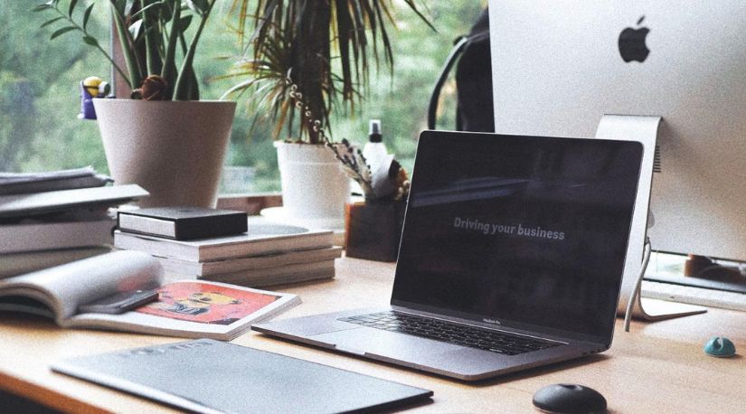 Laptop and iMac on a desk with plants and books