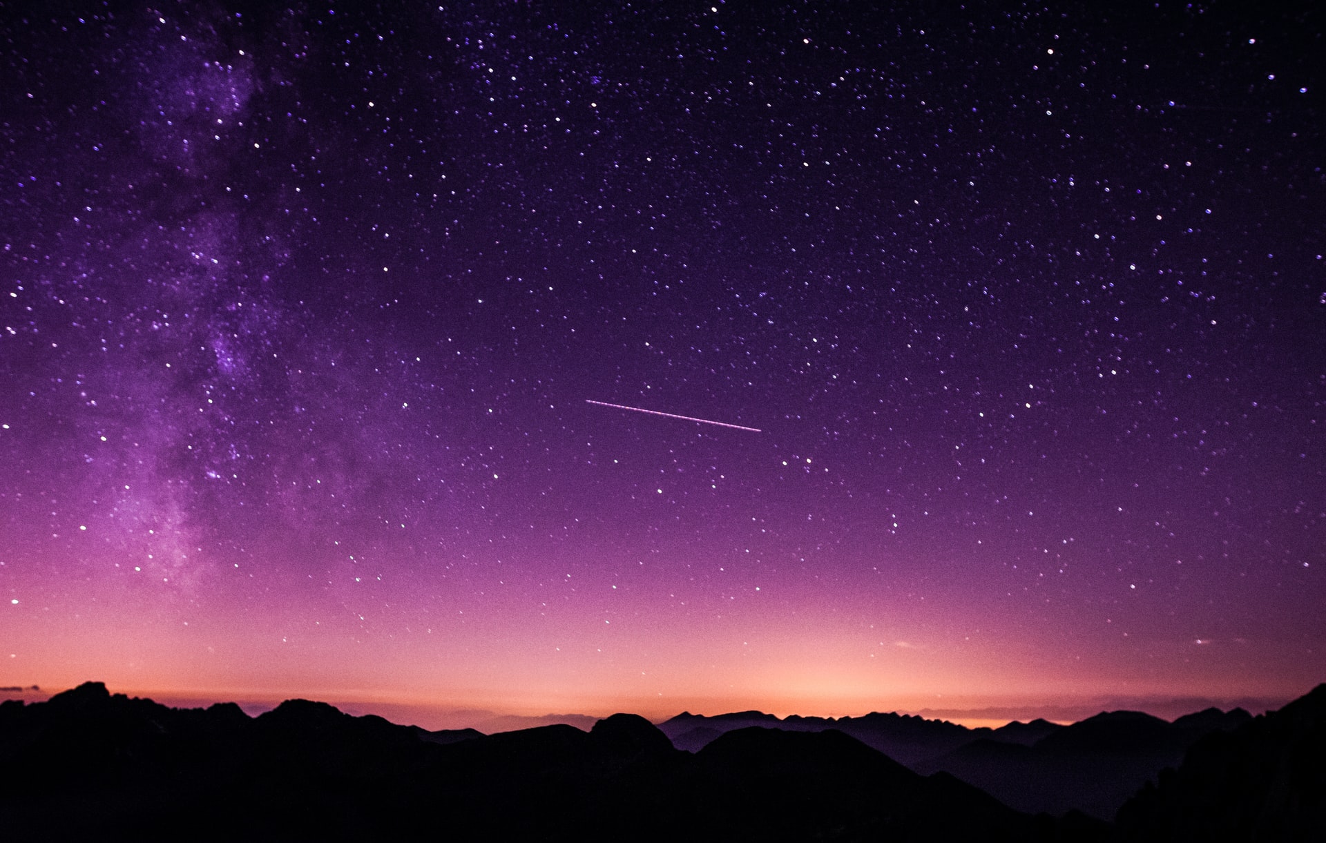 Starry night sky over silhouetted mountains