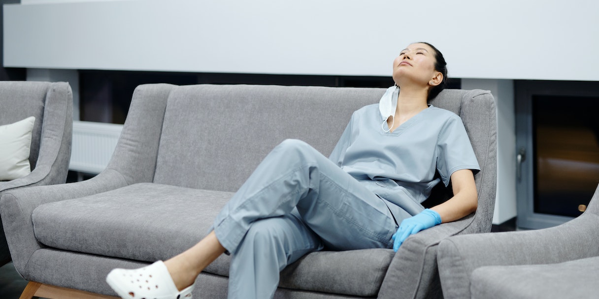 Nurse in scrubs resting on a couch