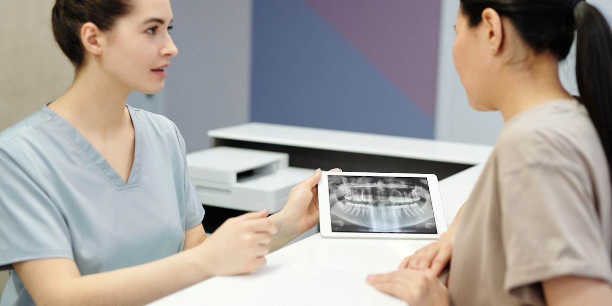 Dental nurse showing a patient an x-ray on a tablet