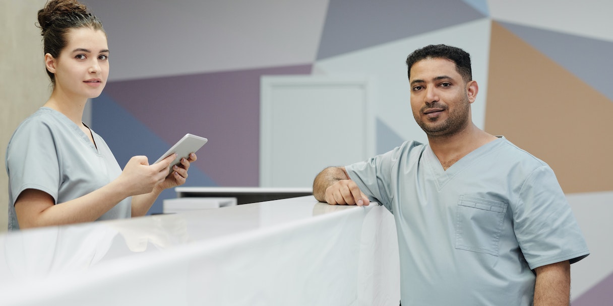 Two medical practice staff members at a reception desk