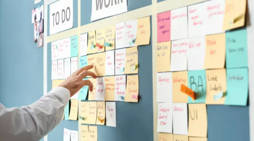Hand arranging sticky notes on a task board