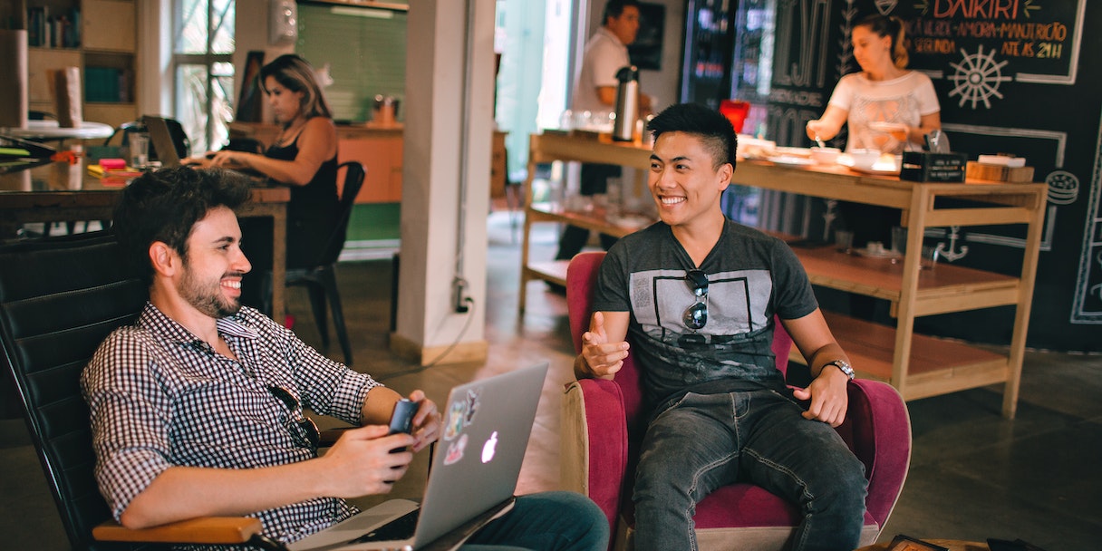 Two men laughing together in a co-working cafe