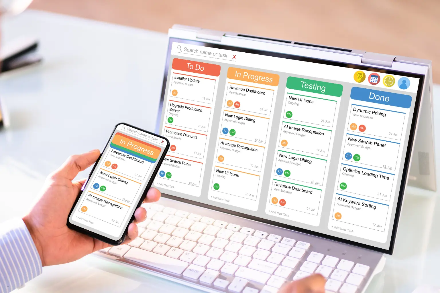 Hands holding phone and laptop showing kanban board