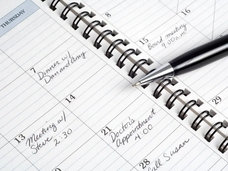 Appointment scheduling software shown in a planner with handwritten notes for meetings and doctor appointments