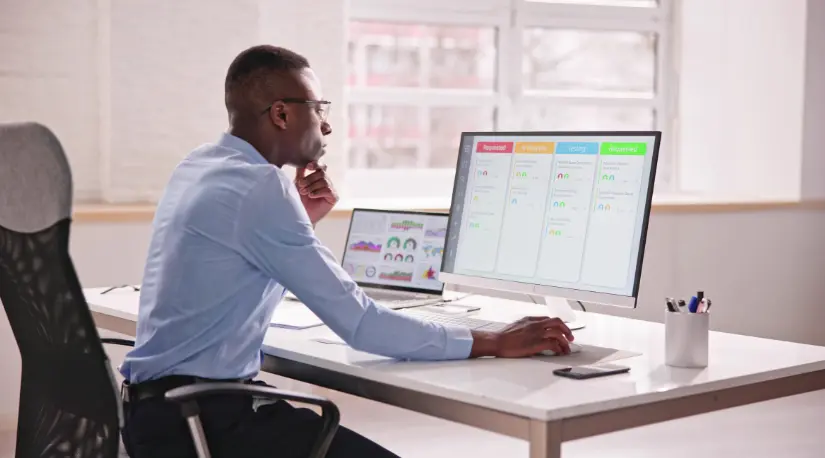 Man reviewing scheduling dashboard on desktop monitor