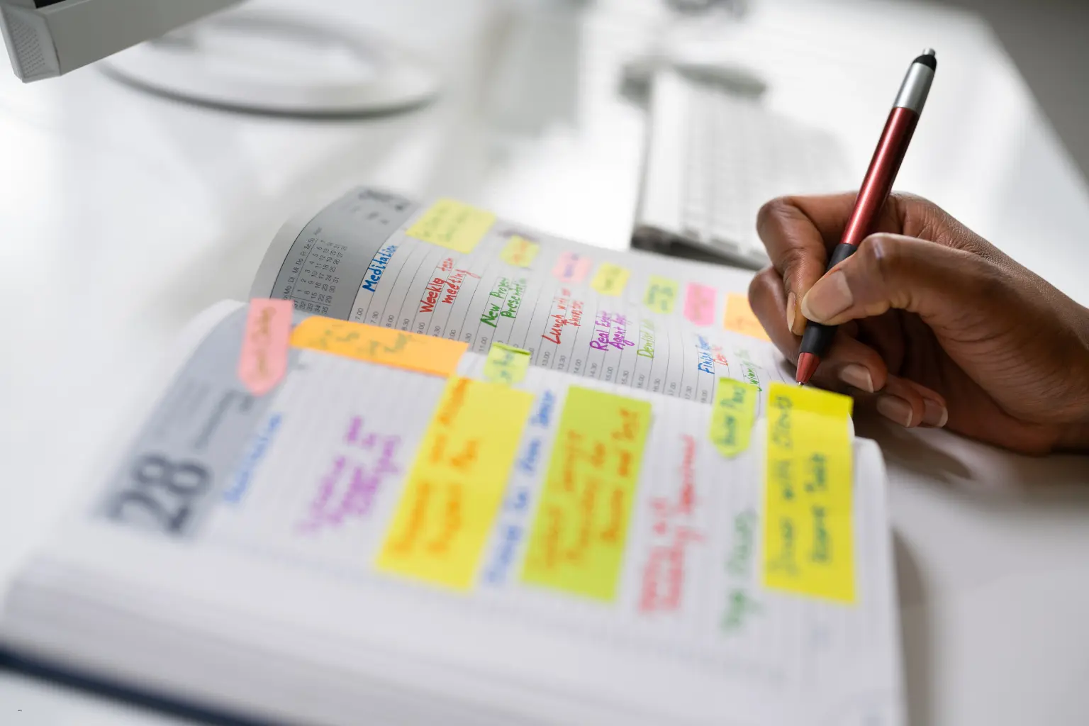 Hand writing with pen in a colorful sticky-note planner