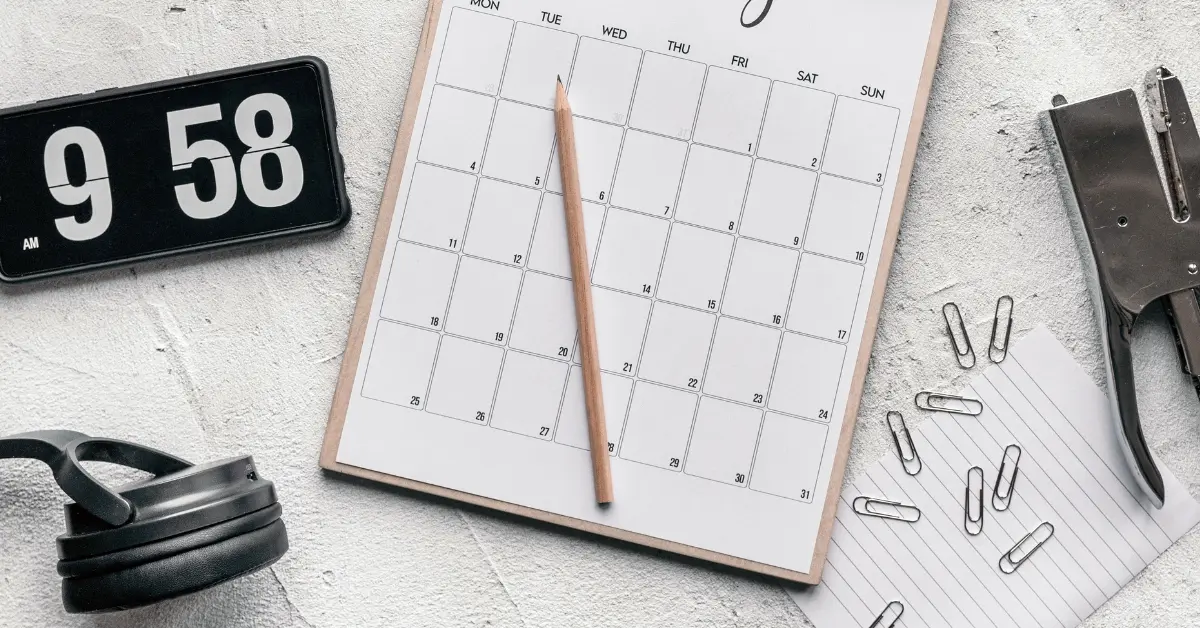 Open source booking software idea shown with a pencil on a blank monthly calendar beside office supplies.