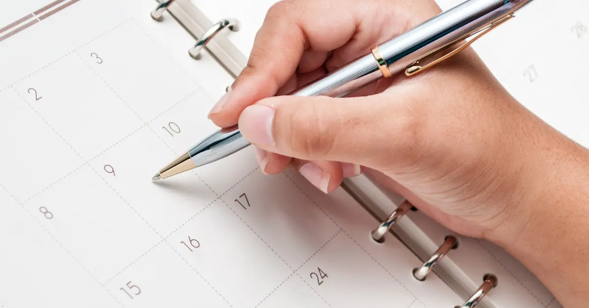 Open source scheduling tools concept with a person writing in a planner calendar