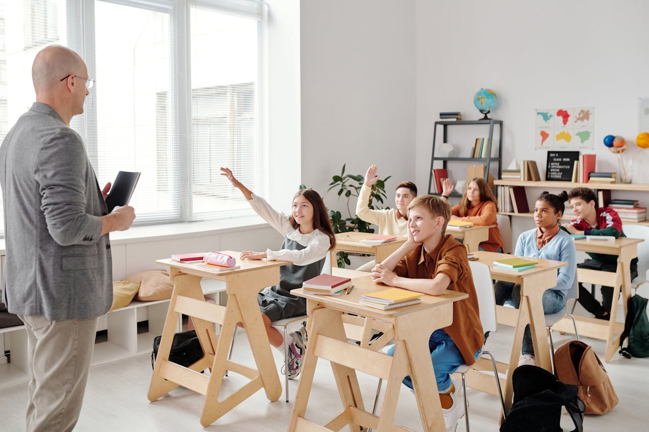 Teacher and students in a classroom raising hands