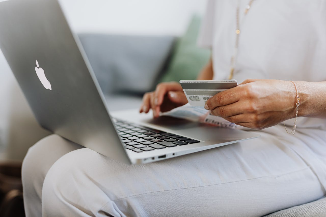 Photo of someone holding a credit card near a laptop
