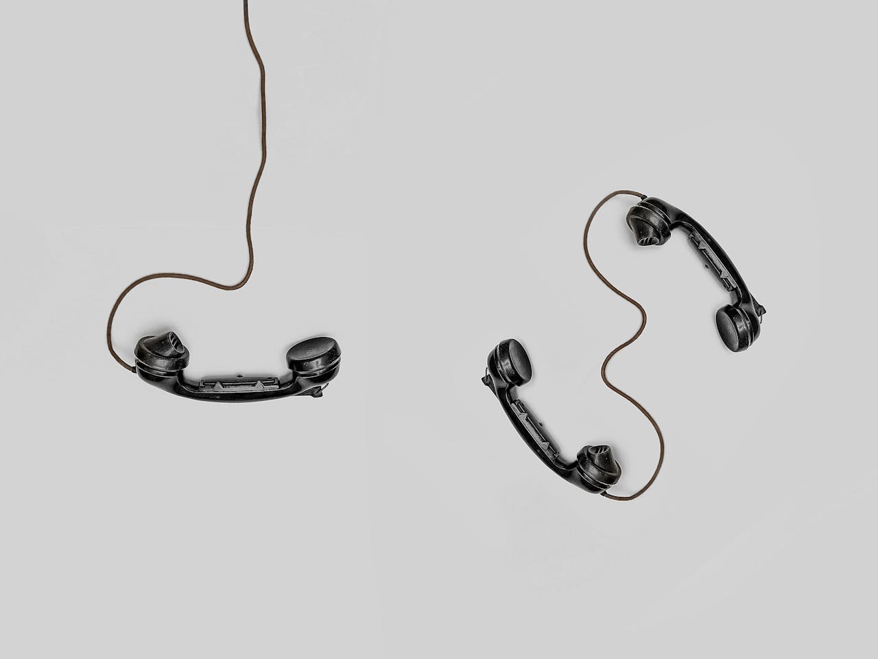 Two vintage telephone handsets on a plain background