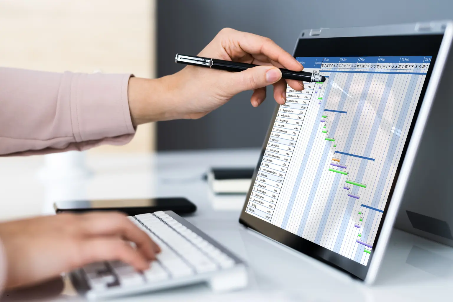 Hand pointing pen at a scheduling gantt chart on tablet