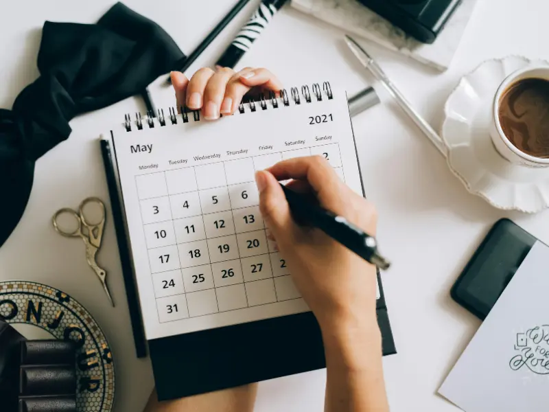 scheduling app monthly calendar planner showing May 2021 with hand marking a date