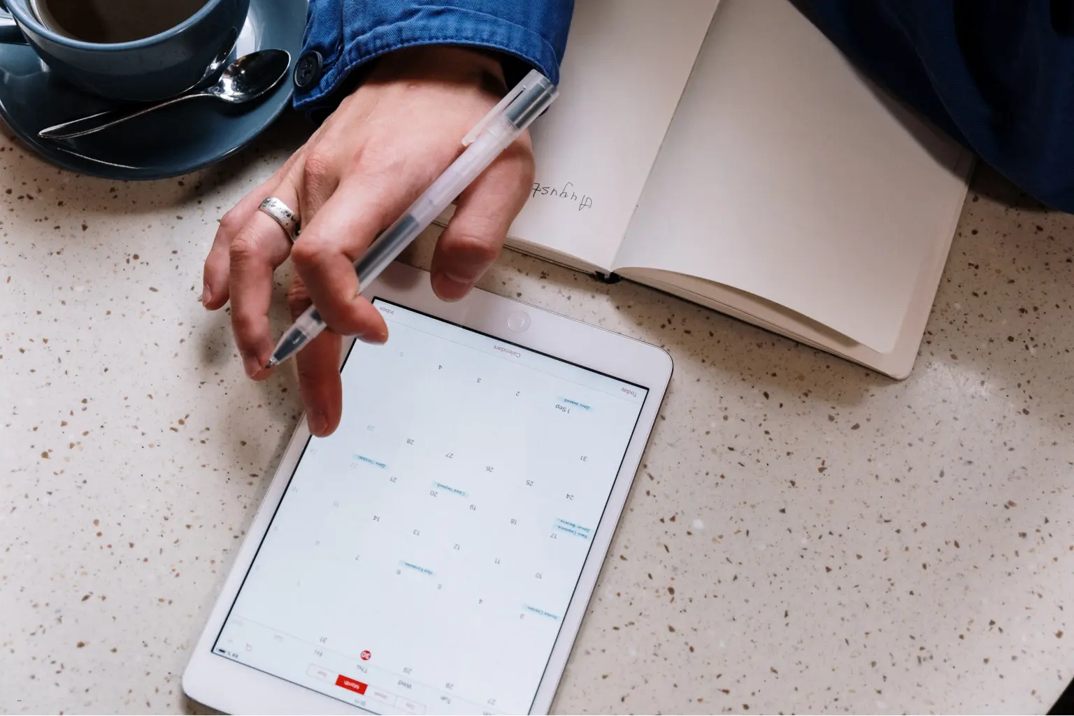 Hand holding a pen over a tablet calendar