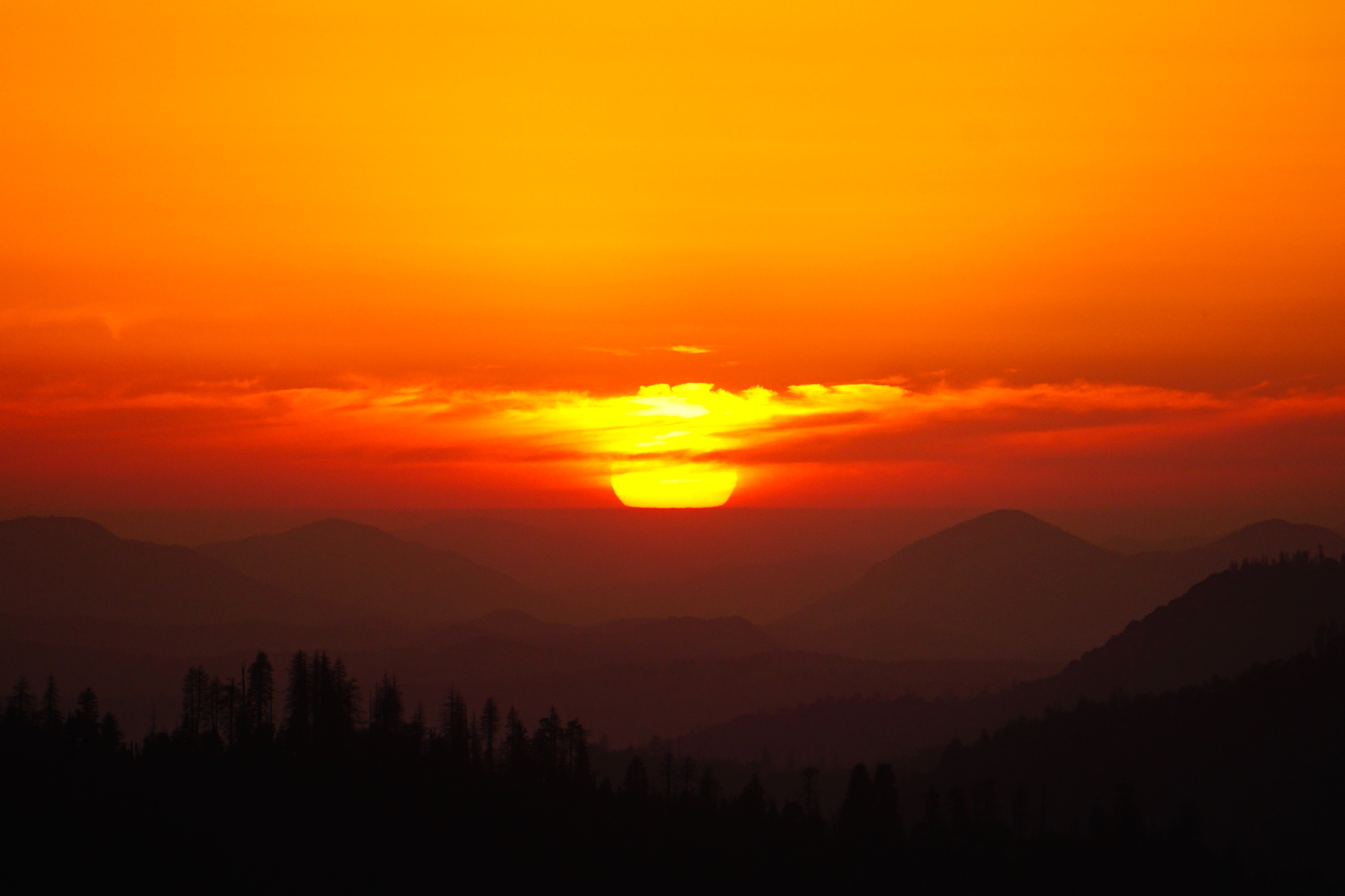 Sunset over silhouetted mountains and forest