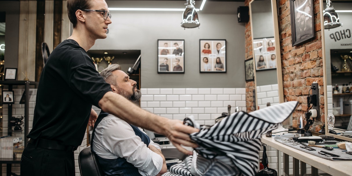 Barber trimming a customer's beard in a barbershop