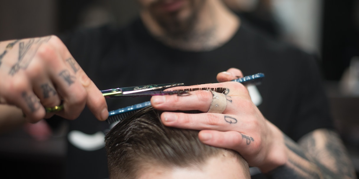 Barber cutting a client's hair with scissors
