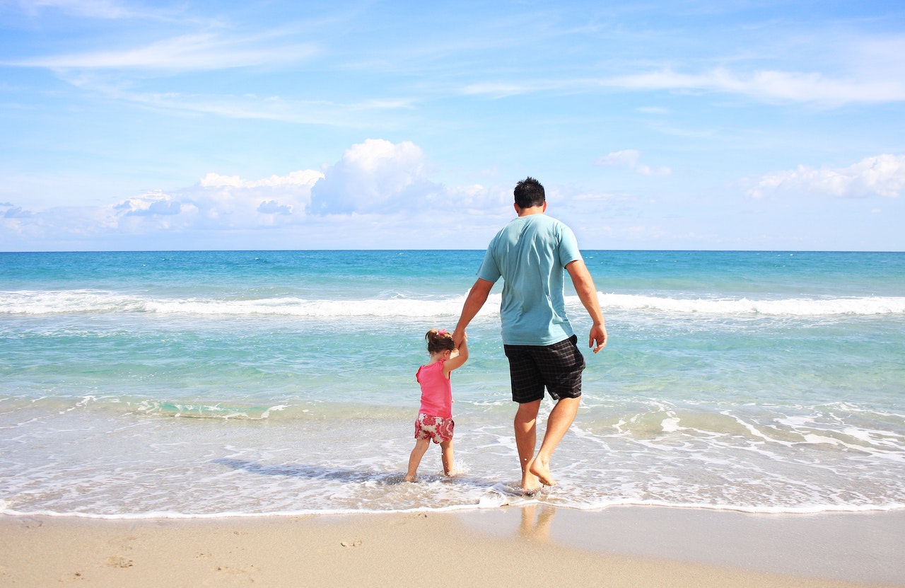 Father and daughter walking along the beach