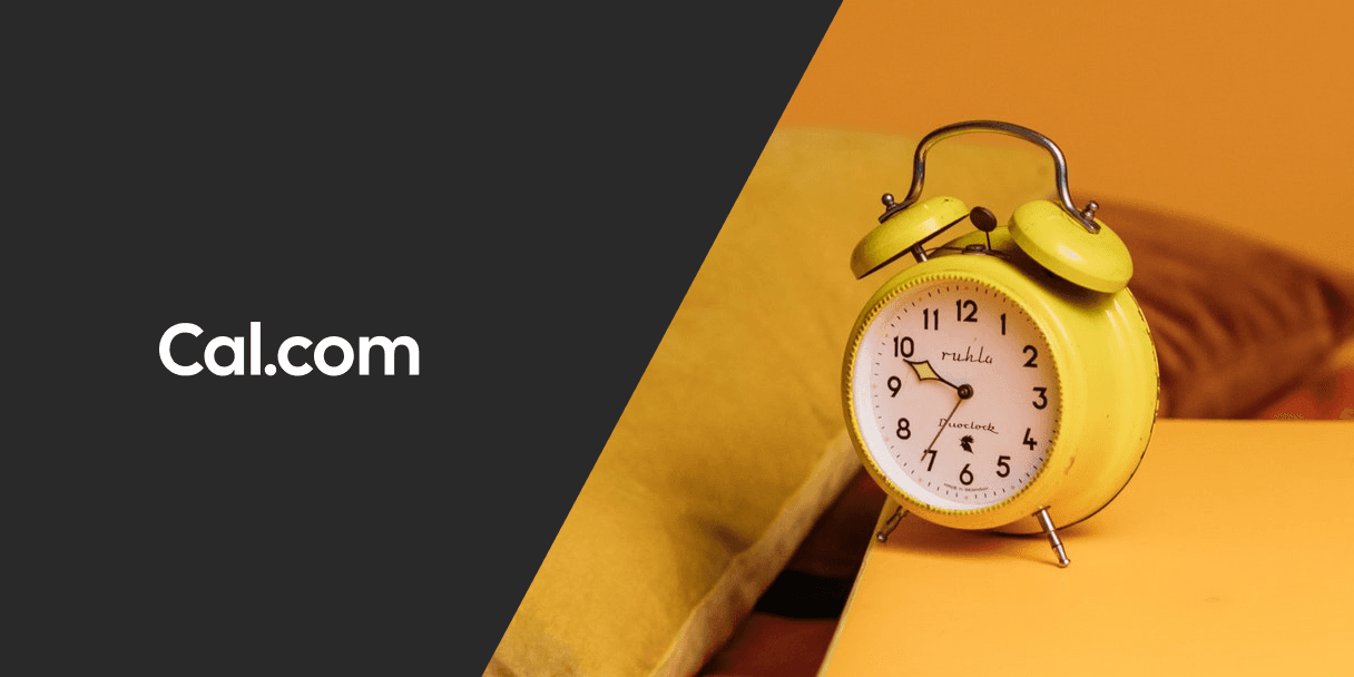 Yellow alarm clock on cushions beside Cal.com logo