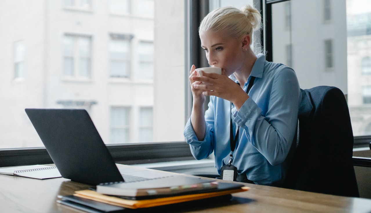 Woman drinking coffee at her laptop