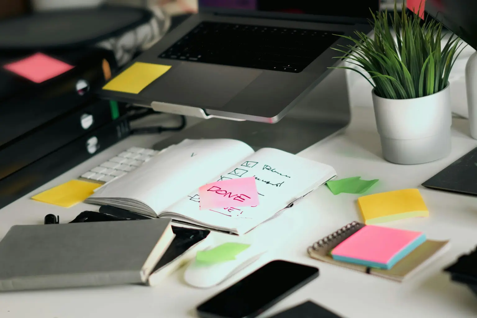 Desk with laptop, notebook, and colorful sticky notes
